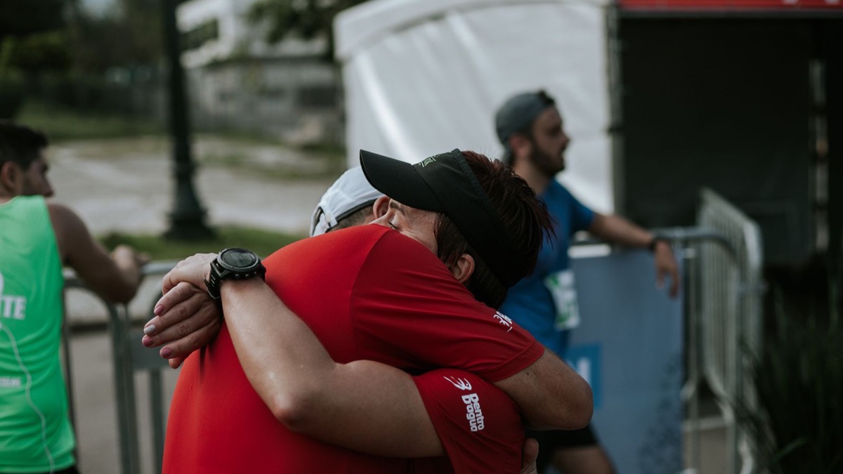 Two runners embracing at a race finish line